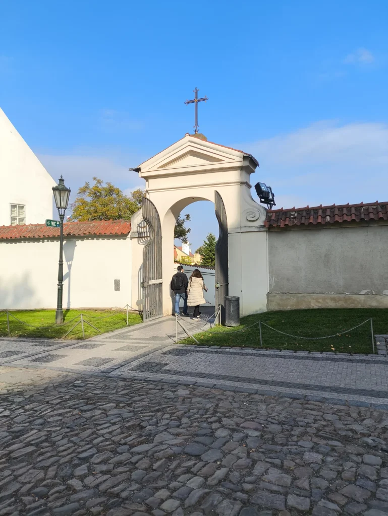 The gateway in the wall beyond the grassy area.